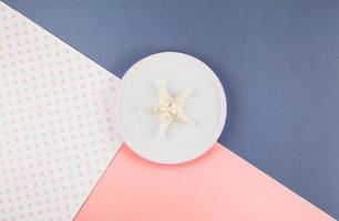 Plate with seashells on color paper background photo