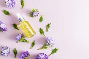 a bottle with a dropper on a pastel background with autumn flowers. unique active cosmetics. preservation of youthful skin. top view. a copy space. photo