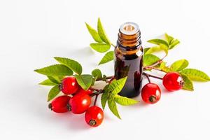 a medical bottle with a dark glass dropper with organic rosehip seed oil on a white background among ripe berries. Mock-up. photo