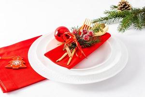 white plates with red napkins and Christmas decorations on a white background. festive serving in the classical style. photo