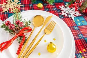 servicio festivo de la mesa de navidad o año nuevo en el estilo clásico de tonos rojos y blancos con ramas de abeto verde, adornos navideños. foto