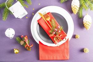 hermosa porción de año nuevo de la mesa festiva con platos, servilletas rojas, ramas de abeto, conos. el concepto de servir la mesa de año nuevo. foto