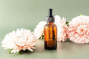 face serum in a cosmetic bottle with a pipette against the background of autumn flowers. unique active cosmetics. prevention of age-related changes.