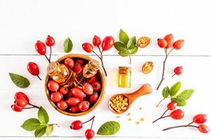 top view of several bottles with a lid with organic oil or essential oil of rosehip seeds in a wooden bowl. a natural remedy. photo