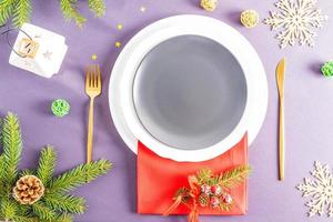 top view of the festive empty plate on the New Year's or Christmas table with a spruce branch, a lantern and confetti. A blank layout for your food. photo