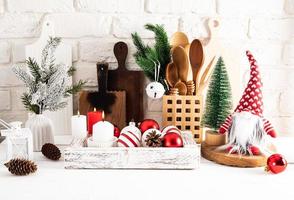Front view of eco-friendly wooden kitchen utensils and Christmas decorations in a wooden box on a white wooden table against a brick wall. photo