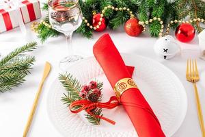 Serving a Christmas table with a plate, gold cutlery, Christmas decorations and gifts. front view.