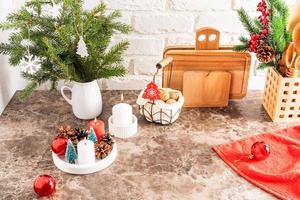 part of a marble countertop in the kitchen with a bouquet of spruce branches, a tray with burning candles, decorations for the new year and Christmas. photo