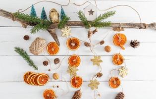 New Year's garland handmade from natural organic dried oranges, cones on a wooden tree trunk. top view.