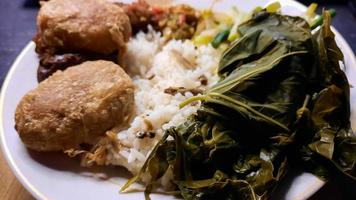 primer plano, menú warteg comida tradicional indonesia, con pasteles de patata y hojas frescas de mandioca 01 foto