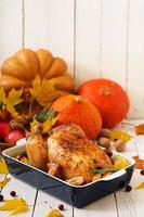 Roasted turkey garnished with cranberries on a rustic style table decorated with pumpkins, orange, apples and autumn leaf. Thanksgiving Day. photo