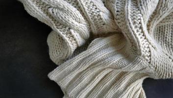 Selective focus Knitted Woolen, Knitwear Fabric Texture, Warm Clothes for Fall and Winter, Woven, Woolen, Sweaters, beige, cream color with Dark Background and copy space photo