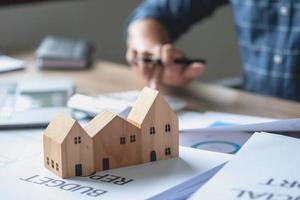 Accountant, businessman, real estate agent, businessman handing model house to customers along with house interest calculation documents for customers to sign. photo