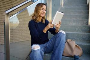mujer alegre disfrutando de la lectura en los pasos foto