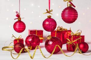 Red Christmas balls, serpentine and New Year's gifts on a light background photo