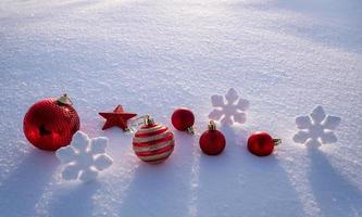 baratijas brillantes, bolas de navidad, copos de nieve y estrellas en la nieve. Decoraciones de navidad foto