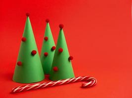 tarjeta de año nuevo. árbol de navidad decorativo hecho de papel, bastón de caramelo sobre un fondo rojo brillante foto