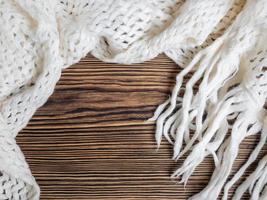 Warm cozy white scarf on a wooden background. Place for text photo