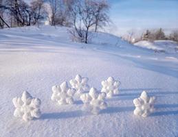 Christmas snowflakes on white snow on the background of trees. Winter frosty sunny day. photo