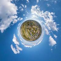 tiny planet in sky with clouds overlooking old town, urban development, historic buildings and crossroads. Transformation of spherical 360 panorama in abstract aerial view. photo