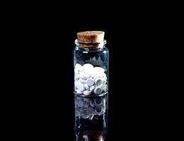 white orange pills in wineglass glass . in jar. in bucket Isolated on black set of capsule and pills inside closeup, photo