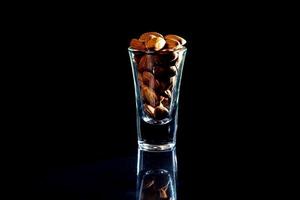 Peeled almond in jar wineglass bucket on a black isolated background. Row of bowls with almond nuts, front view. photo