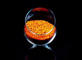 Close up of Raw Masur dal or masoor lentils or pink lentils in a black colored clay bowl on black in wineglass glass jar bucket photo