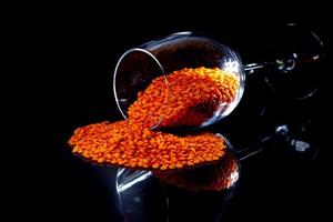 Close up of Raw Masur dal or masoor lentils or pink lentils in a black colored clay bowl on black in wineglass glass jar bucket photo