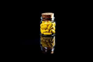 white orange pills in wineglass glass . in jar. in bucket Isolated on black set of capsule and pills inside closeup, photo