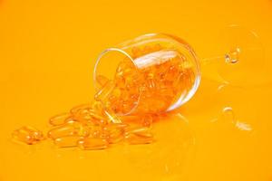 Fish oil capsules. Yellow omega 3 pills in jar on the yellow and orange. fish oil capsules in glass . in jar. in bucket ampoules photo