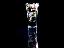 white orange pills in wineglass glass . in jar. in bucket Isolated on black set of capsule and pills inside closeup, photo