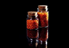 Close up of Raw Masur dal or masoor lentils or pink lentils in a black colored clay bowl on black in wineglass glass jar bucket photo