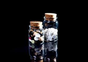 white orange pills in wineglass glass . in jar. in bucket Isolated on black set of capsule and pills inside closeup, photo