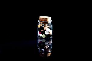 white orange pills in wineglass glass . in jar. in bucket Isolated on black set of capsule and pills inside closeup, photo