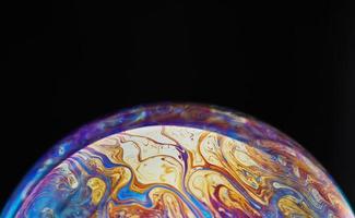 Virtual reality space with abstract multicolor psychedelic planet. Closeup Soap bubble like an alien planet on black background photo