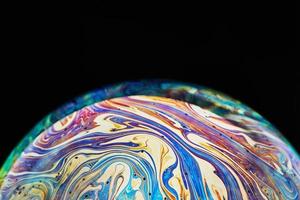 Virtual reality space with abstract multicolor psychedelic planet. Closeup Soap bubble like an alien planet on black background photo