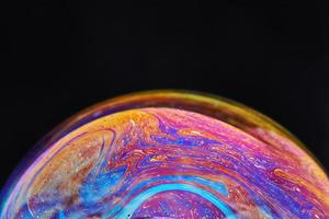 Virtual reality space with abstract multicolor psychedelic planet. Closeup Soap bubble like an alien planet on black background photo