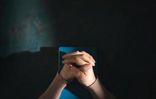 Spirituality, Religion and Hope Concept. Person Praying by Holy Bible on Desk. Symbol of Humility, Supplication,Believe and Faith for Christian People. Top View photo