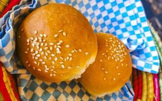 Delicious round buns with sesame seeds on wooden table Mexico. photo