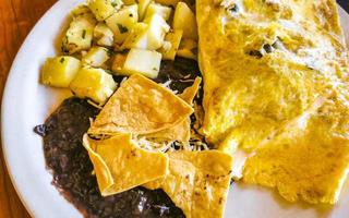 Mexican omelet with black beans potatoes nachos on white plate. photo