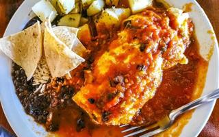 Mexican omelet with black beans potatoes nachos on white plate. photo