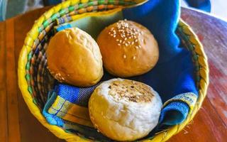 Delicious round buns with sesame seeds on wooden table Mexico. photo