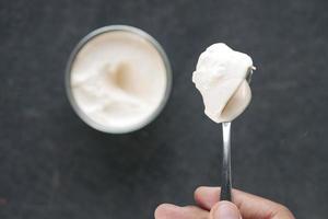 top view of milk cream on a silver spoon and container on background photo