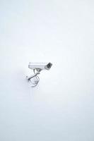 CCTV security camera operating on a white wall with copy space photo