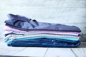 stack of men's shirts and jeans on table photo