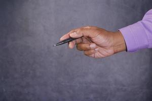 side view of holding a pen pointing something against black background photo