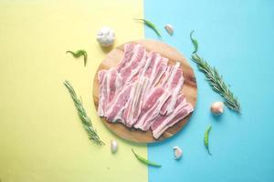 Raw fed bacon strips on chopping board . photo