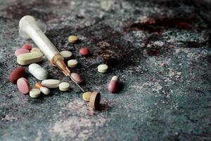 syringe and pills on dark background, close up photo