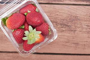Ripe Red Strawberries in a plastic container on table photo