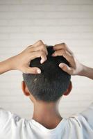 teenage boy Scratching Head Against black background . photo